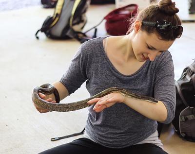 student holding snake in herpetology field trip classroom