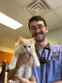 Fitzsimmons wearing scrubs and holding a white cat