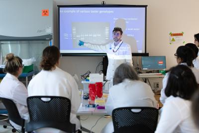 Drew Spacht pointing to an image of an agarose gel in a presentation for lab technicians in the Amgen Biotech Experience.