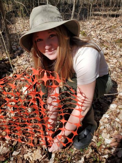 Cheyenne Dang outside crouching next to orange snow fence