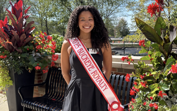 Sophia Walker wearing sash and standing in front of bench and canna flowers