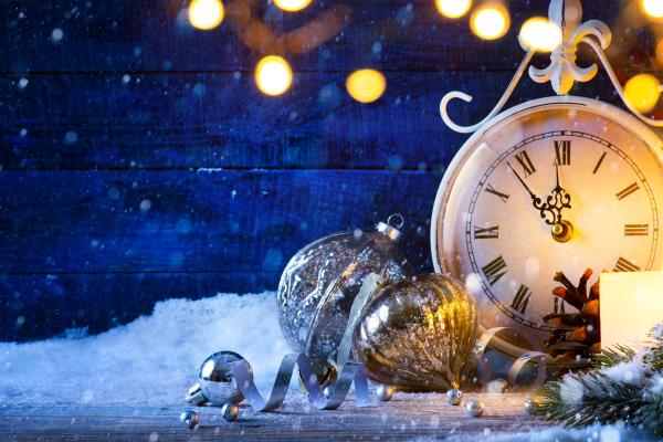 White clock and gold lights in front of blue planks on the snow
