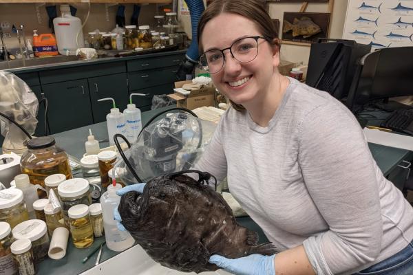 Liz Santos holding anglerfish specimen over lab counter