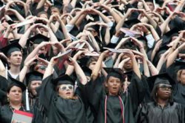 graduates in stadium forming "O" with their arms