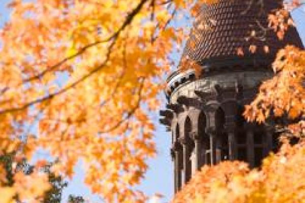closeup of Orton Hall Tower through tree branches and colorful autumn leaves