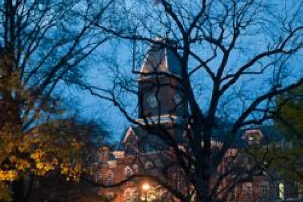 view of university hall through silhouettes of trees at dusk in winter
