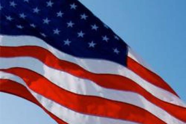 Closeup of American flag billowing in the wind with blue sky behind