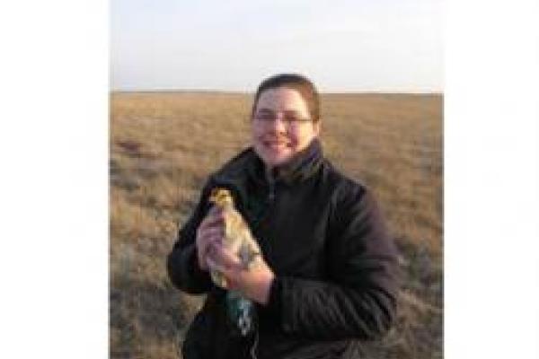 Jackie Augustine holding prairie chicken in open field
