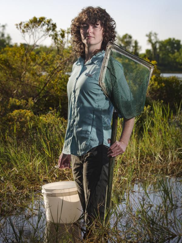 Caitlin Weid holding bucket and net in body of water