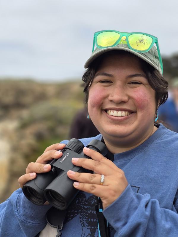 Maddie Ybarra holding binoculars in the field