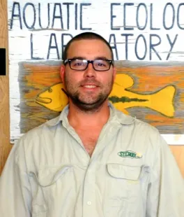 head and shoulders shot of Neal Banaszak standing in front of AEL poster